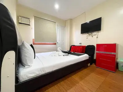 a bedroom with a bed with a red dresser and a tv at Chanel Paris Hotel powered by Cocotel in Manila