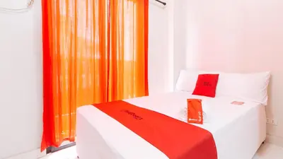 a bedroom with a bed with an orange curtain at RedDoorz near NAIA Terminal 1 in Manila