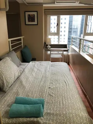 a bed in a room with a desk and a window at Loft condo beside Shangri-La Fort in Manila