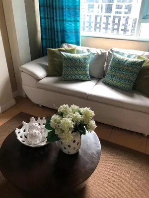 a living room with a couch and a table with flowers at Loft condo beside Shangri-La Fort in Manila