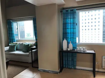 a living room with a couch and two windows at Loft condo beside Shangri-La Fort in Manila