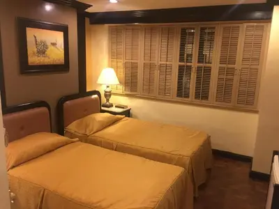 a hotel room with two beds and a lamp at Lourdes Family Suites Makati powered by Cocotel in Manila