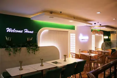 a restaurant with tables and chairs and a green wall at Lourdes Family Suites Makati powered by Cocotel in Manila