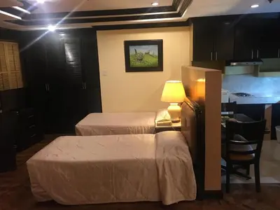 a room with two beds and a table with a lamp at Lourdes Family Suites Makati powered by Cocotel in Manila