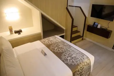 a room with a bed and a staircase with a television at Mella Hotel Manila near NAIA Airport in Manila