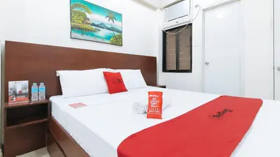 a bedroom with a white bed with red accents at RedDoorz near Pasay Taft in Manila
