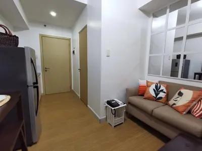 a living room with a couch and a door at Liam's Pad at grace residences in Manila