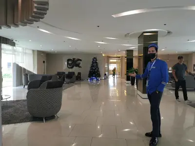a man wearing a mask in a lobby with a christmas tree at Liam's Pad at grace residences in Manila