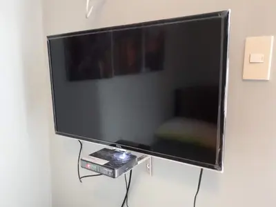 a large flat screen tv hanging on a wall at 1BR with Balcony Overlooking Pool Chateau Elysee Near NAIA in Manila