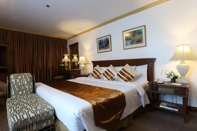 a hotel room with a large bed and a chair at Tiara Oriental Hotel Makati powered by Cocotel in Manila