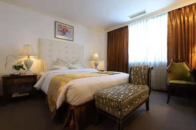 a hotel room with a large bed and a chair at Tiara Oriental Hotel Makati powered by Cocotel in Manila