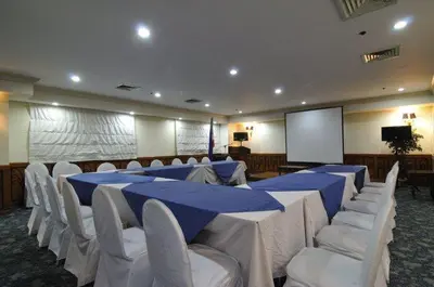 a conference room with tables and white chairs and a screen at Tiara Oriental Hotel Makati powered by Cocotel in Manila