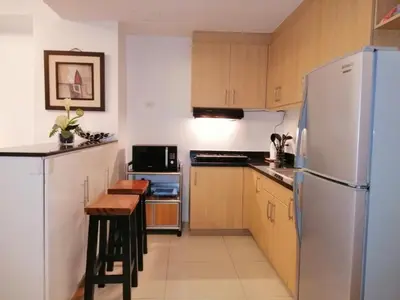 a kitchen with a refrigerator and a table in it at Prime Avant BGC Location Apartments by PH Staycation in Manila