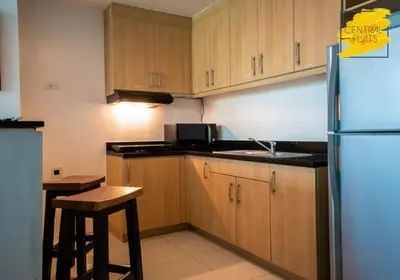 a kitchen with wooden cabinets and a sink and a refrigerator at Prime Avant BGC Location Apartments by PH Staycation in Manila