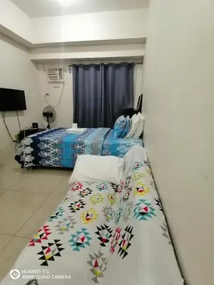 a bedroom with two beds and a bedspread with flowers at The Beacon Makati Staycation Suites in Manila