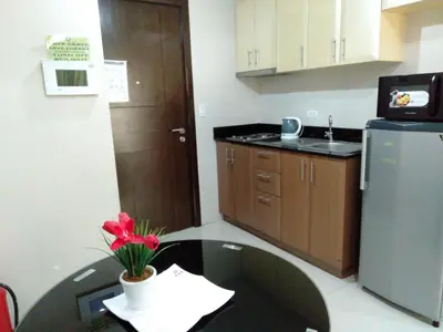a small kitchen with a table with a flower on it at One Palm Tree Villas close to Manila Airport - Terminal 3 in Manila