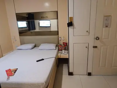a small bedroom with a bed and a mirror at Hotel Sogo Malate in Manila