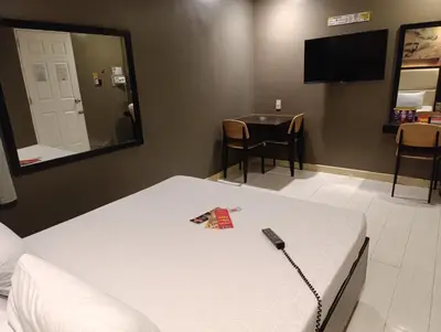 a bedroom with a bed with a remote control on it at Hotel Sogo Malate in Manila