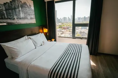a bedroom with a large bed with a large window at 1898 Hotel Colonia En Las Filipinas in Manila