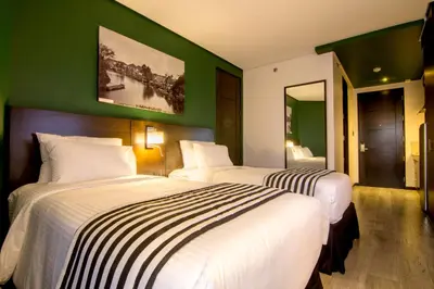 two beds in a hotel room with green walls at 1898 Hotel Colonia En Las Filipinas in Manila