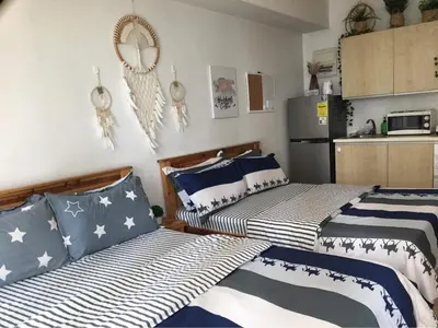 two beds in a room with a kitchen at GREENFIELD studio w/ 2 queen across Shangrila in Manila