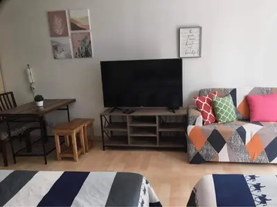 a living room with a flat screen tv and a couch at GREENFIELD studio w/ 2 queen across Shangrila in Manila