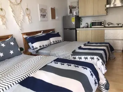two beds in a room with a kitchen at GREENFIELD studio w/ 2 queen across Shangrila in Manila