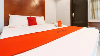 a bed with an orange and white blanket on it at RedDoorz near Bambang Station in Manila