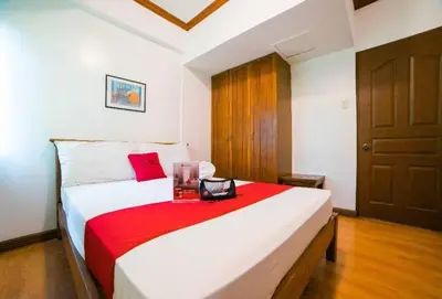a bedroom with a large white bed with a red blanket at RedDoorz at Moonwalk Paranaque in Manila