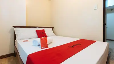 a bed with red and white pillows on it at RedDoorz at Moonwalk Paranaque in Manila