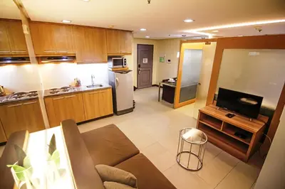 a large kitchen with wooden cabinets and a television at BSA Twin Towers in Manila