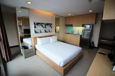 a bedroom with a large white bed and a kitchen at BSA Twin Towers in Manila