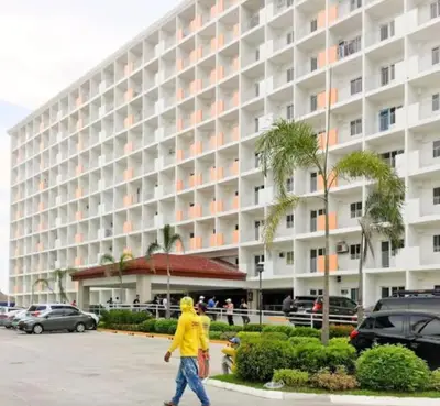a man walking in front of a large building at Affordable condotel near Manila Airport in Manila