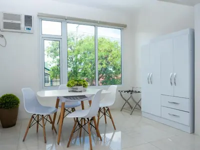 a white kitchen with a table and white chairs at City Park Hotel Residences in Manila