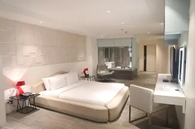 a bedroom with a white bed and a living room at City Park Hotel Residences in Manila