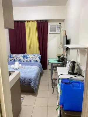 a small room with a bed and a table with a kitchen at Shanilyn Residency Urban Deca Towers EDSA mandaluyong UNLIMITED INTERNET AND NETFLIX in Manila