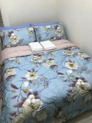 a bed with a blue blanket with flowers on it at Shanilyn Residency Urban Deca Towers EDSA mandaluyong UNLIMITED INTERNET AND NETFLIX in Manila