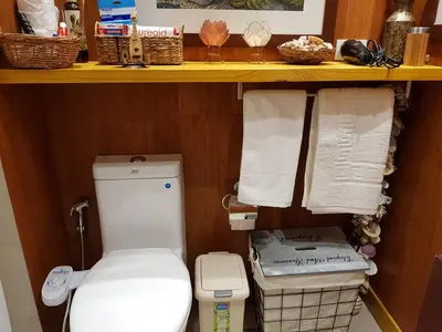 a bathroom with a toilet and towels on a shelf at Stay Amare Green La Salle Taft in Manila