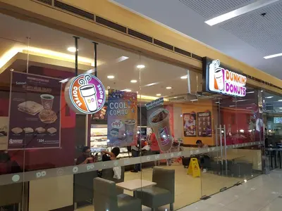 a dunkin donuts store with a glass window and signs at Stay Amare Green La Salle Taft in Manila