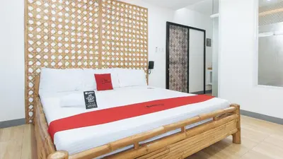 a bedroom with a large bed with a wooden headboard at RedDoorz at DBuilders Rooms Lower Bicutan in Manila
