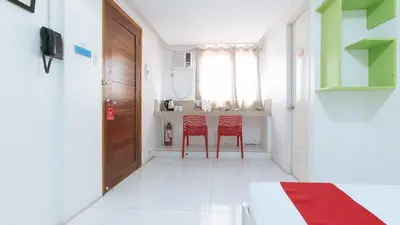 a room with two red chairs and a table at RedDoorz at DBuilders Rooms Lower Bicutan in Manila