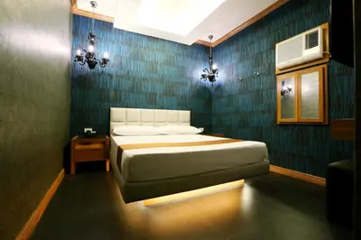 a bedroom with a bed and a blue wall at Hotel Ava Cuneta in Manila