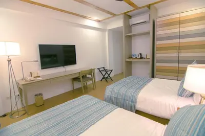 a hotel room with two beds and a desk with a tv at Thunderbird Resorts - Rizal in Binangonan
