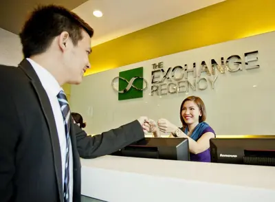 a man and a woman shaking hands at a cash register at The Exchange Regency Residence Hotel Managed by HII in Manila