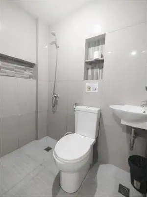 a white bathroom with a toilet and a sink at Sulit Budget Hotel VMapa in Manila