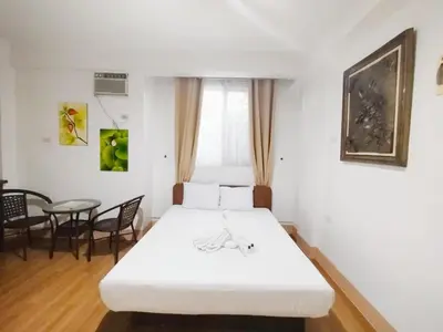 a white bed in a room with a table at Sulit Budget Hotel VMapa in Manila