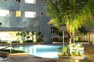a swimming pool with a palm tree in front of a building at Condotel Type in Manila