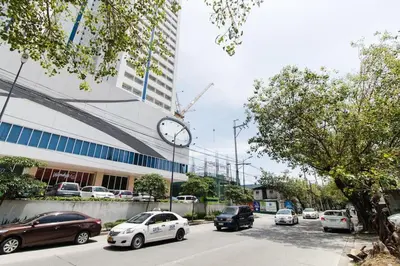 a clock on the side of a building with cars parked at Condotel @JAZZ Residences in Manila