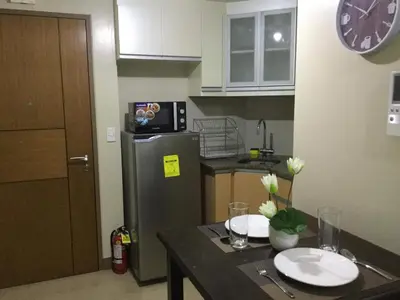 a kitchen with a refrigerator and a table with plates on it at Palm Tree Villas 2 in Manila