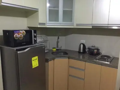 a kitchen with a microwave on top of a refrigerator at Palm Tree Villas 2 in Manila